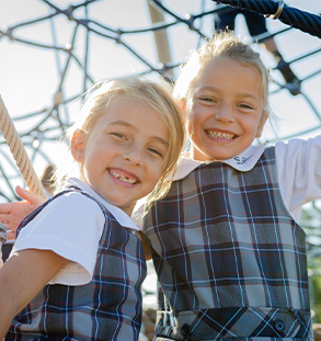 Two young female students on playground equipment